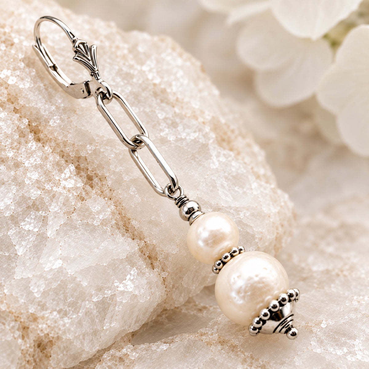 Close-up of a Callie freshwater pearl earring showing paperclip chain, pearl detailing and fleur-de-lis leverback
