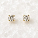 Capri Gold Crystal Stud Earrings featuring brilliant round European crystals in a classic four-prong champagne gold setting displayed on the Carabella white quartz slab.