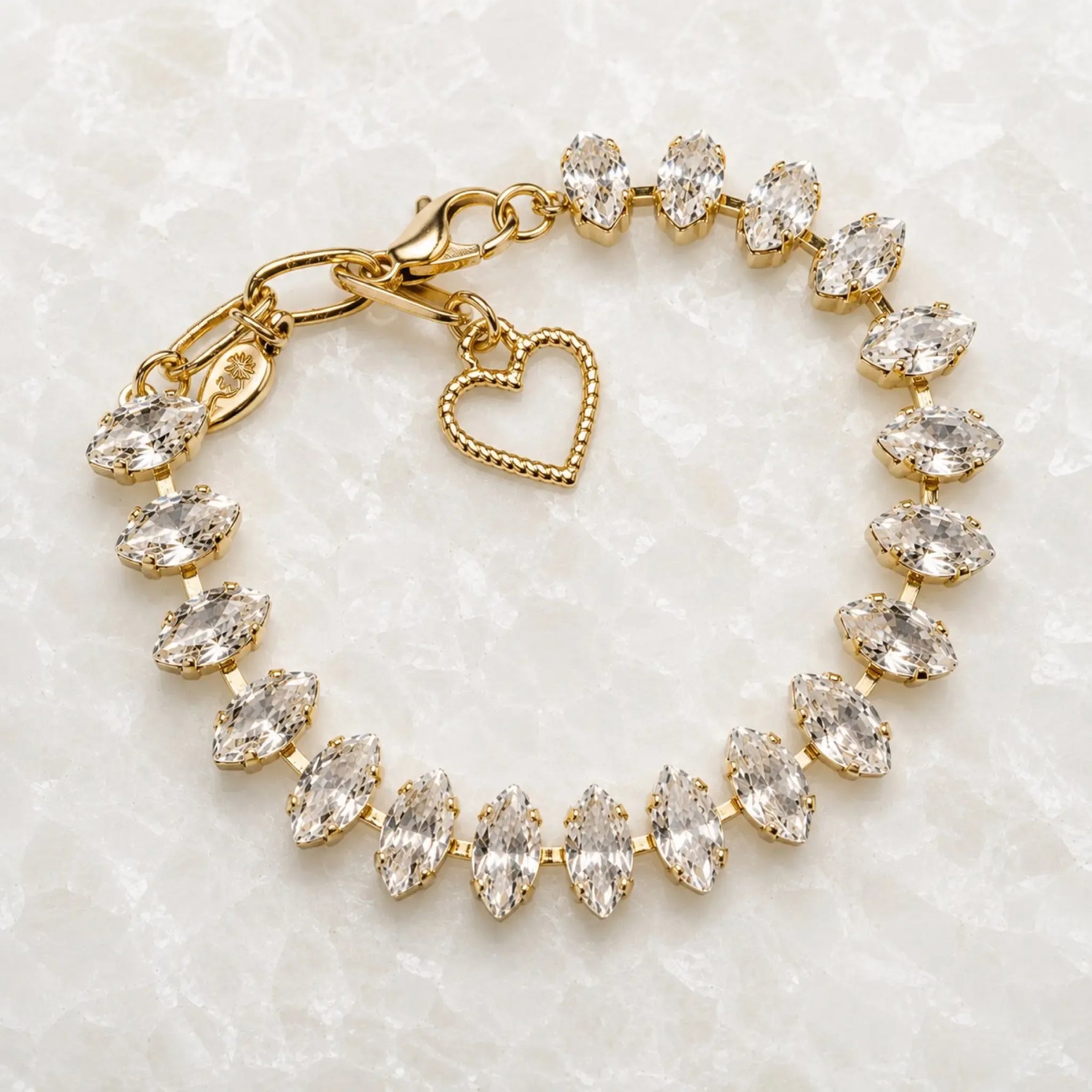 Capri Gold Crystal Tennis Bracelet handcrafted in Canada featuring marquise-cut European crystals in a champagne gold finish displayed on the Carabella white quartz slab.