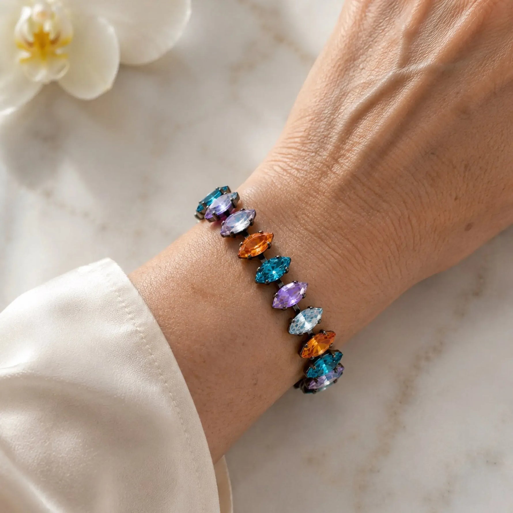 Close-up of the Capri Multi-Color Crystal Tennis Bracelet worn on the wrist, showcasing vibrant marquise-cut crystals and refined gunmetal settings.