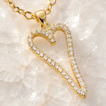 Extreme macro of the Cara gold Heart A necklace highlighting the pavé crystal setting, polished gold finish, bail, and craftsmanship.