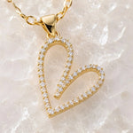 Extreme macro of the Cara gold Heart B necklace highlighting the pavé crystal setting, polished gold finish, bail, and craftsmanship.