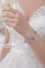 Blue crystal charm bracelet worn with lace bridal gown