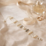 Luxury bridal pearl bracelet with sterling silver toggle clasp styled on ivory silk beside wedding invitation, ribbon, perfume, and rings in soft natural light