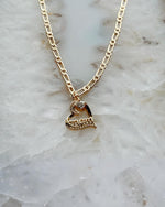 Eternal Love “Mom” heart necklace in gold-plated finish with cubic zirconia accents, styled on soft stone for a timeless and elegant Carabella by Cheryl presentation.