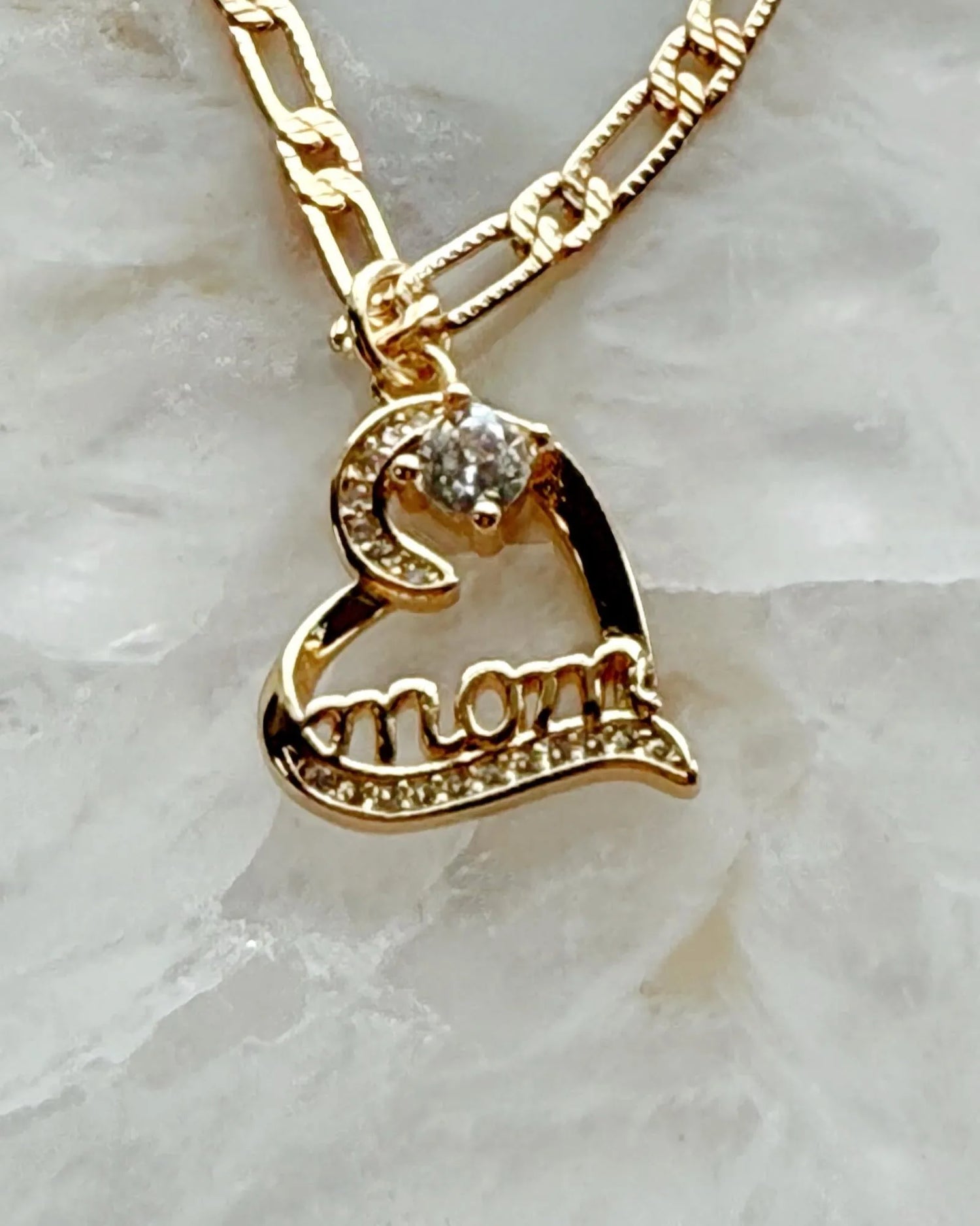 Close-up of the Eternal Love heart pendant engraved with “mom,” featuring cubic zirconia sparkle and gold-plated warmth in a refined Carabella by Cheryl luxury style.