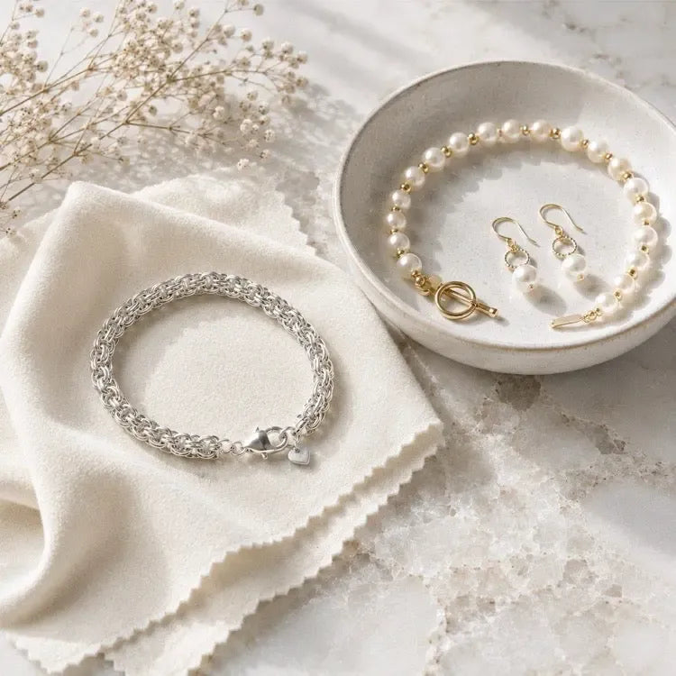 Sterling silver bracelet and pearl jewellery arranged with a soft polishing cloth for jewellery care.