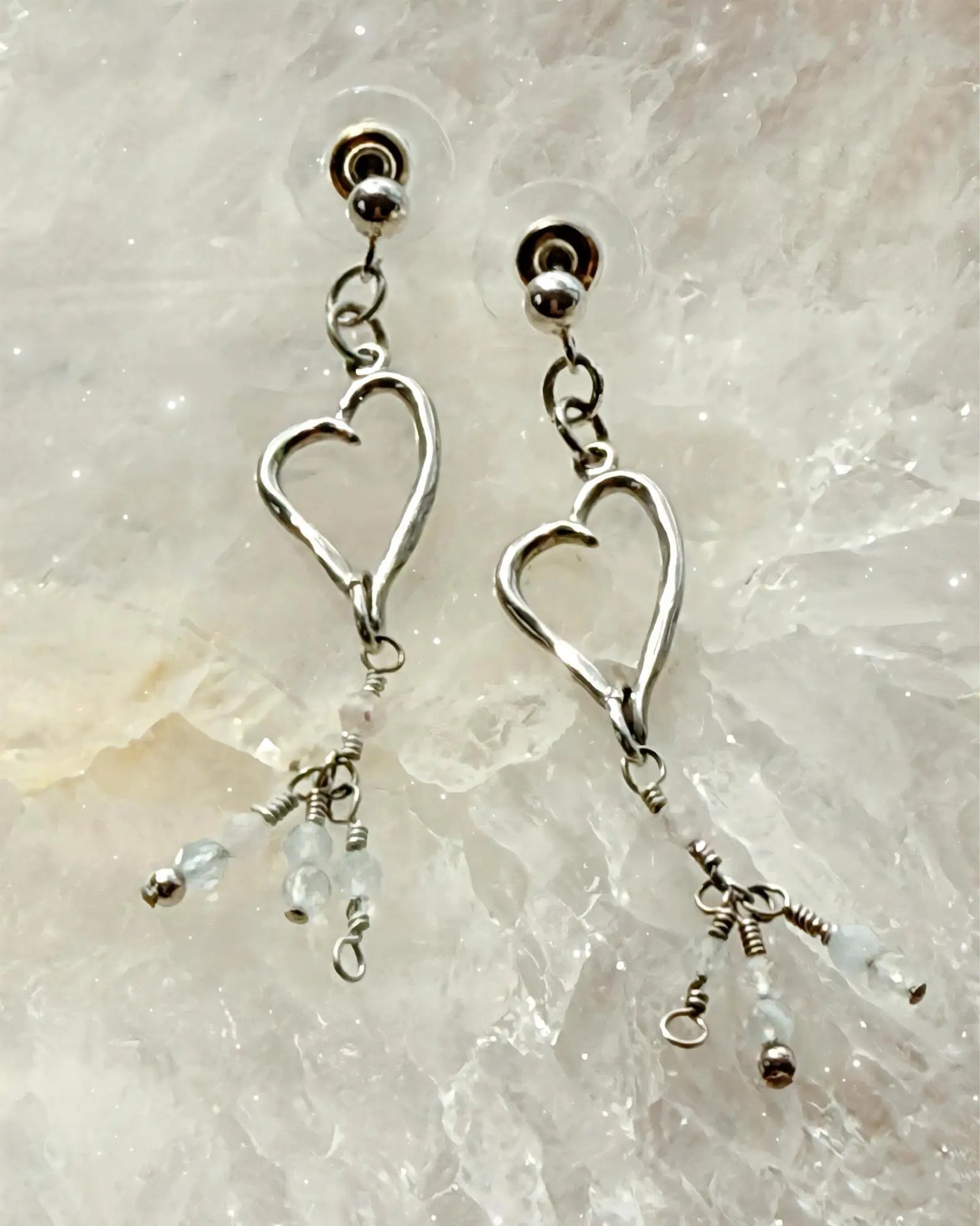 Morganite gemstone heart drop earrings in sterling silver, styled on a luminous crystal surface for an elegant and refined Carabella presentation.