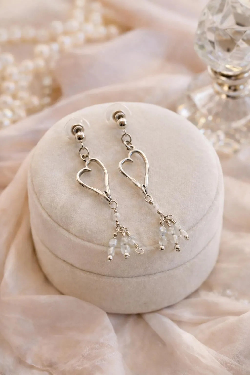 Sterling silver heart earrings with Morganite gemstones styled in a refined luxury still life, evoking timeless sophistication and polished femininity.