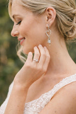 Model wearing Morganite heart drop earrings in sterling silver, photographed outdoors in natural light for a romantic yet understated Carabella lifestyle moment.