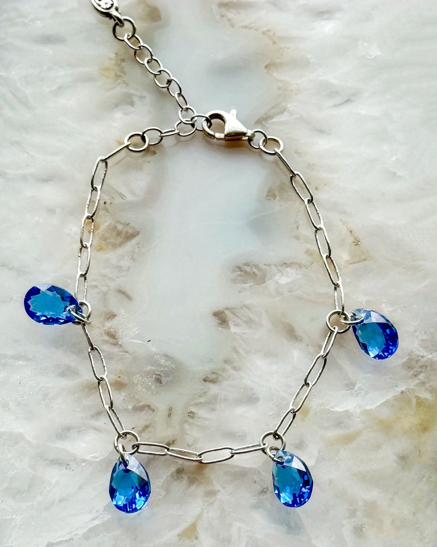Sapphire crystal drop bracelet with blue Austrian crystals on a silver chain, styled on a soft marble background for something blue bridal jewelry