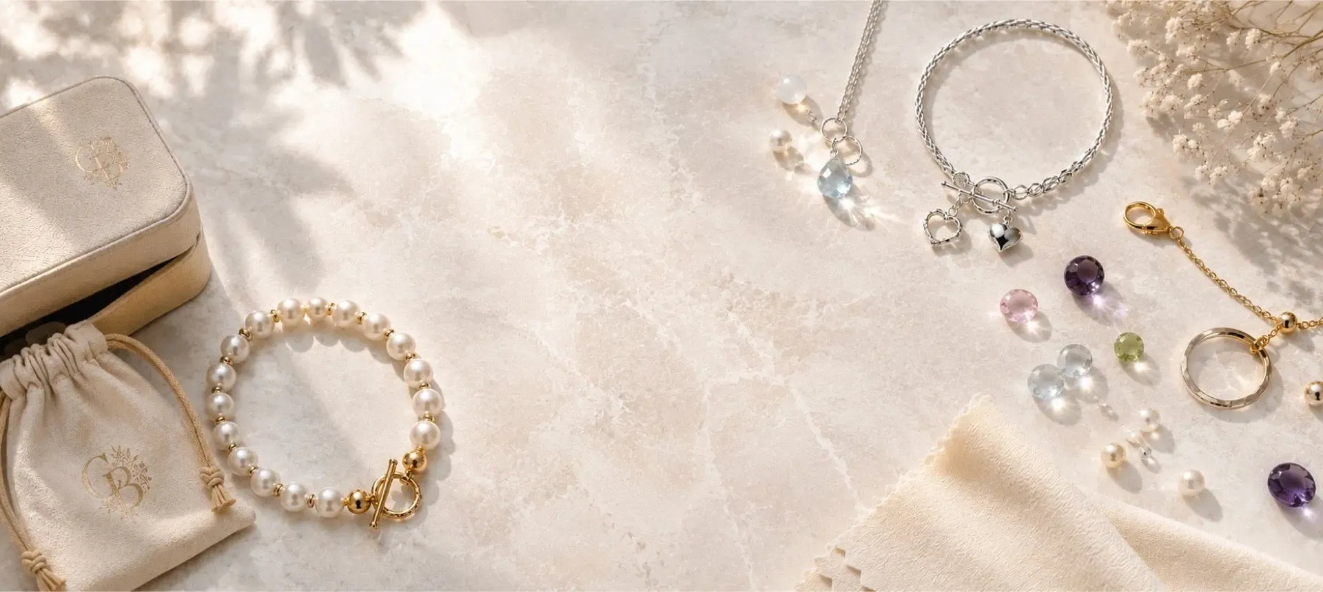 Carabella jewellery, pearls, gemstones and silver and gold details arranged with jewellery packaging and care accessories.