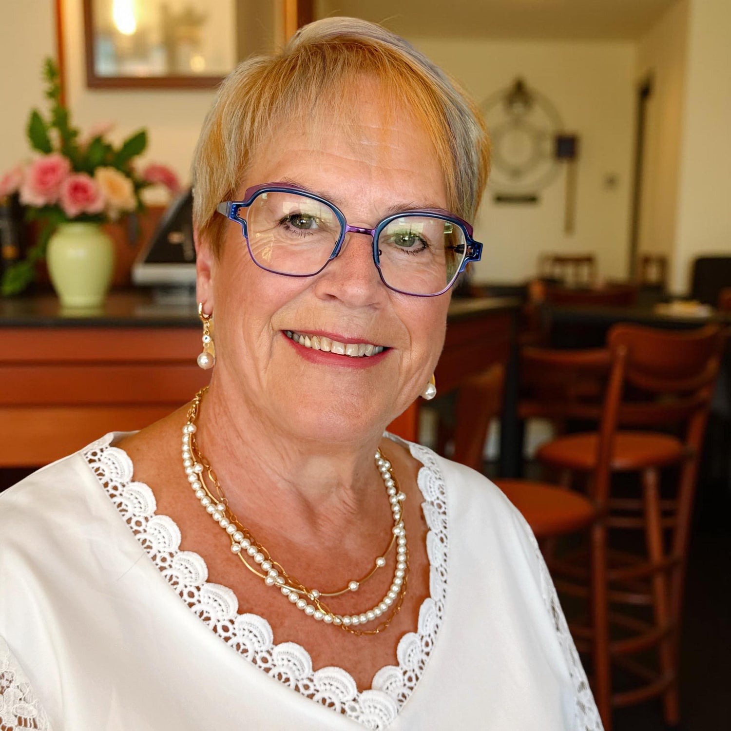 Portrait of Cheryl Borisenko, Founder and Designer of Carabella by Cheryl, wearing handcrafted pearl jewellery while seated in a café.