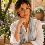 Woman wearing the Ella silver sapphire crystal bracelet in a peaceful garden while dressed in elegant travel attire.