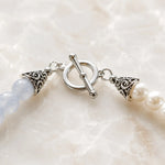 Close-up of the Elodie Bracelet highlighting the sterling silver toggle clasp, decorative end caps, blue chalcedony gemstones, and Snow Czech crystal pearls.