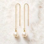 Handcrafted gold threader pearl earrings with Swarovski® Crystal Pearls displayed on white quartz.