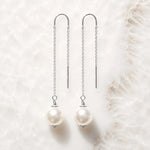 Handcrafted sterling silver threader pearl earrings with Swarovski® Crystal Pearls displayed on white quartz.