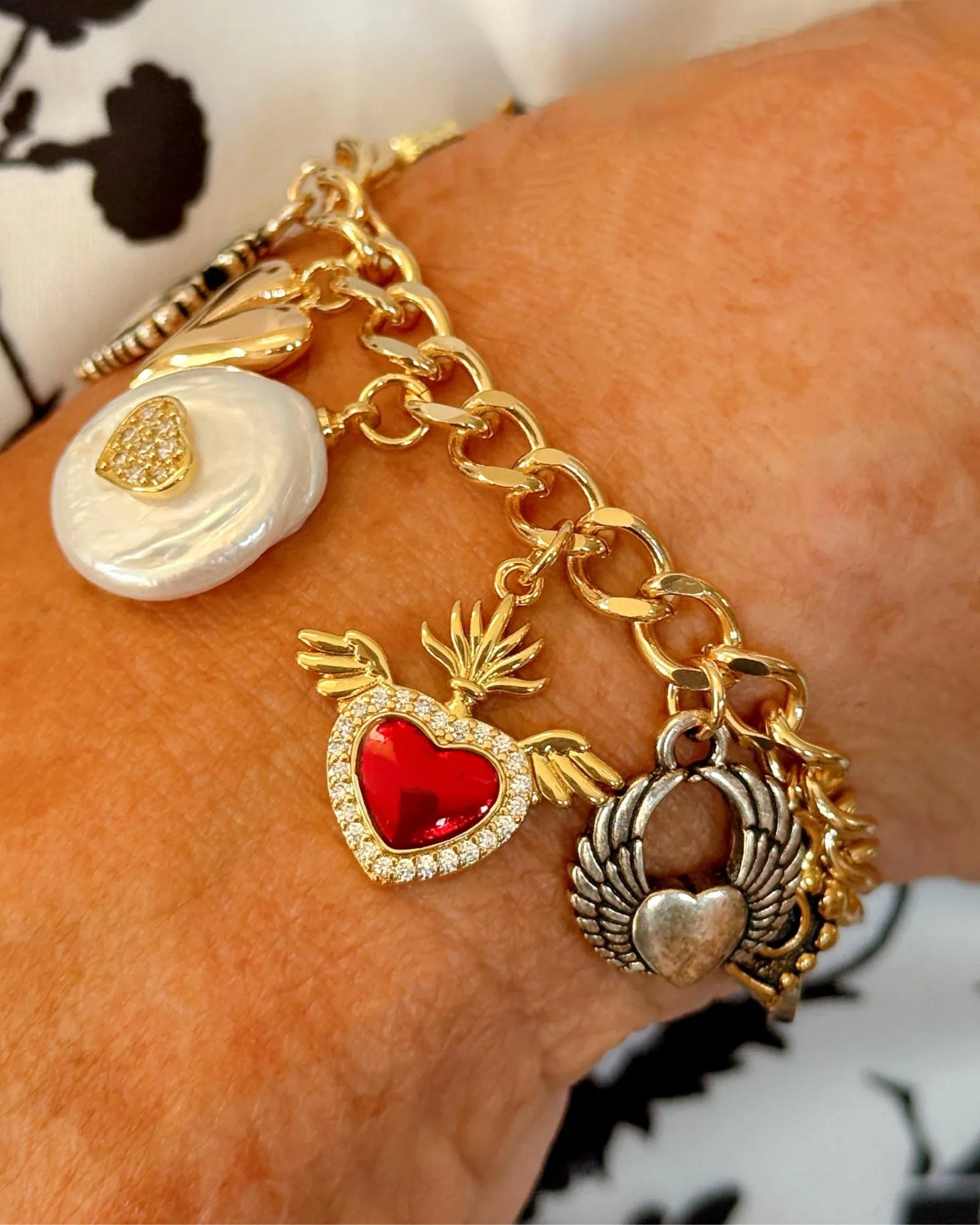 Esme charm bracelet worn on the wrist, featuring delicate heart charms in mixed metals for a feminine, modern look.