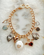Close-up of Esme charm bracelet highlighting polished heart charms in mixed silver and gold tones.