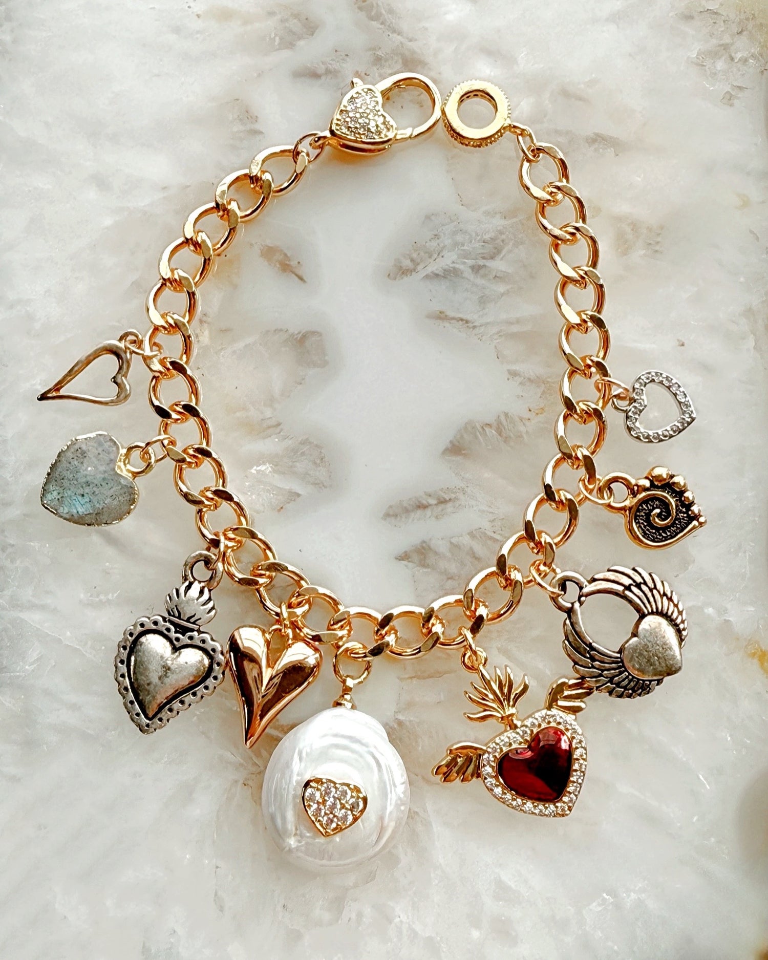 Close-up of Esme charm bracelet highlighting polished heart charms in mixed silver and gold tones.