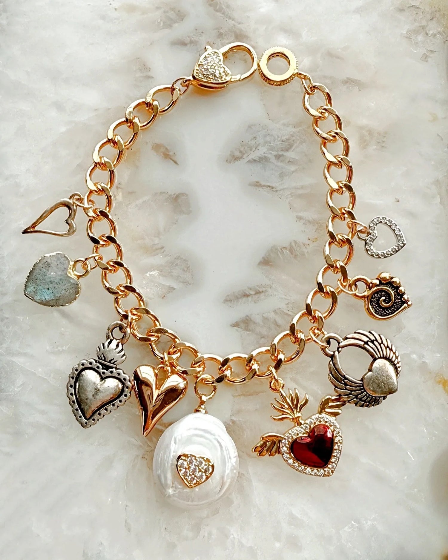 Close-up of Esme charm bracelet highlighting polished heart charms in mixed silver and gold tones.