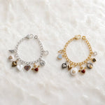 Esme Charm Bracelet Collection shown in both silver and gold finishes on white quartz, highlighting handcrafted heart charms and signature mixed-metal styling.