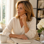 Elegant woman wearing the Esme Gold Charm Bracelet with an ivory cashmere sweater in a refined professional setting.