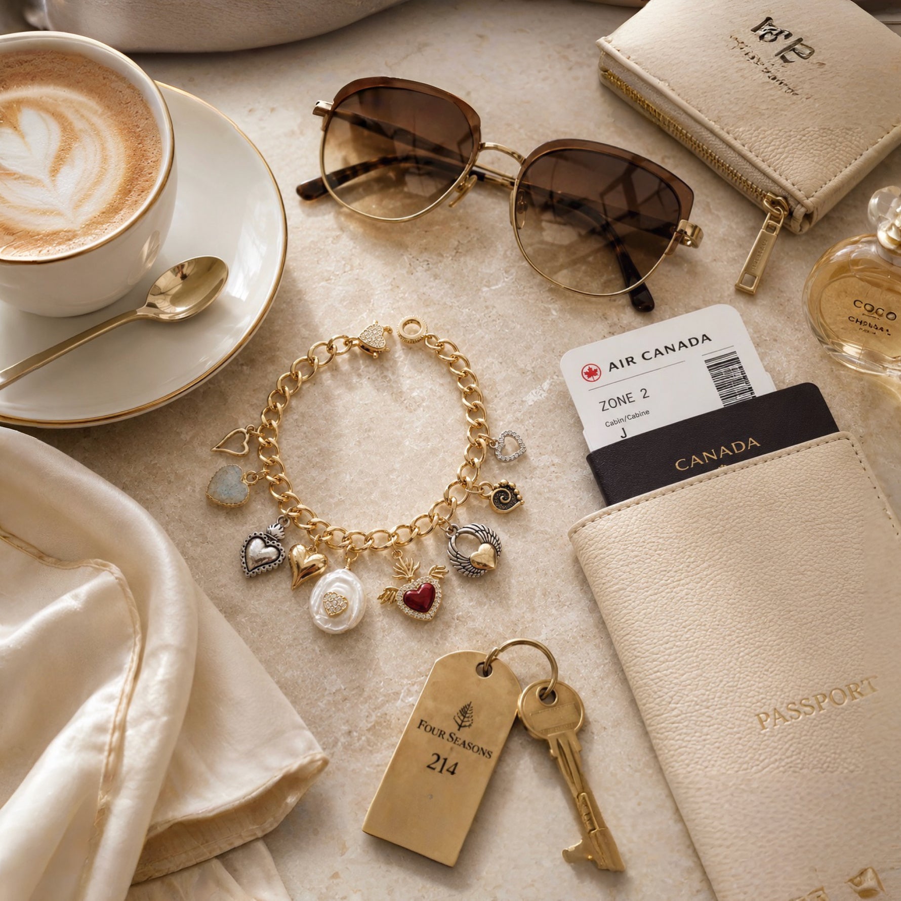 Esme Gold Charm Bracelet styled with a passport, sunglasses, cappuccino, and travel essentials, highlighting handcrafted luxury and timeless travel style.