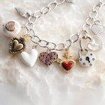 Close-up of the handcrafted Esme Silver Charm Bracelet showcasing mixed-metal heart charms, baroque pearl charm, crystal accents, and polished sterling silver-plated chain by Carabella by Cheryl.