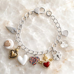 Esme Silver Charm Bracelet on white quartz featuring heart charms, crystal heart clasp, pearl charm, enamel heart, and handcrafted mixed-metal design by Carabella by Cheryl.