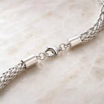Macro detail of the Evelyn bracelet showing the polished lobster clasp, woven silver termination, end caps and jump rings.