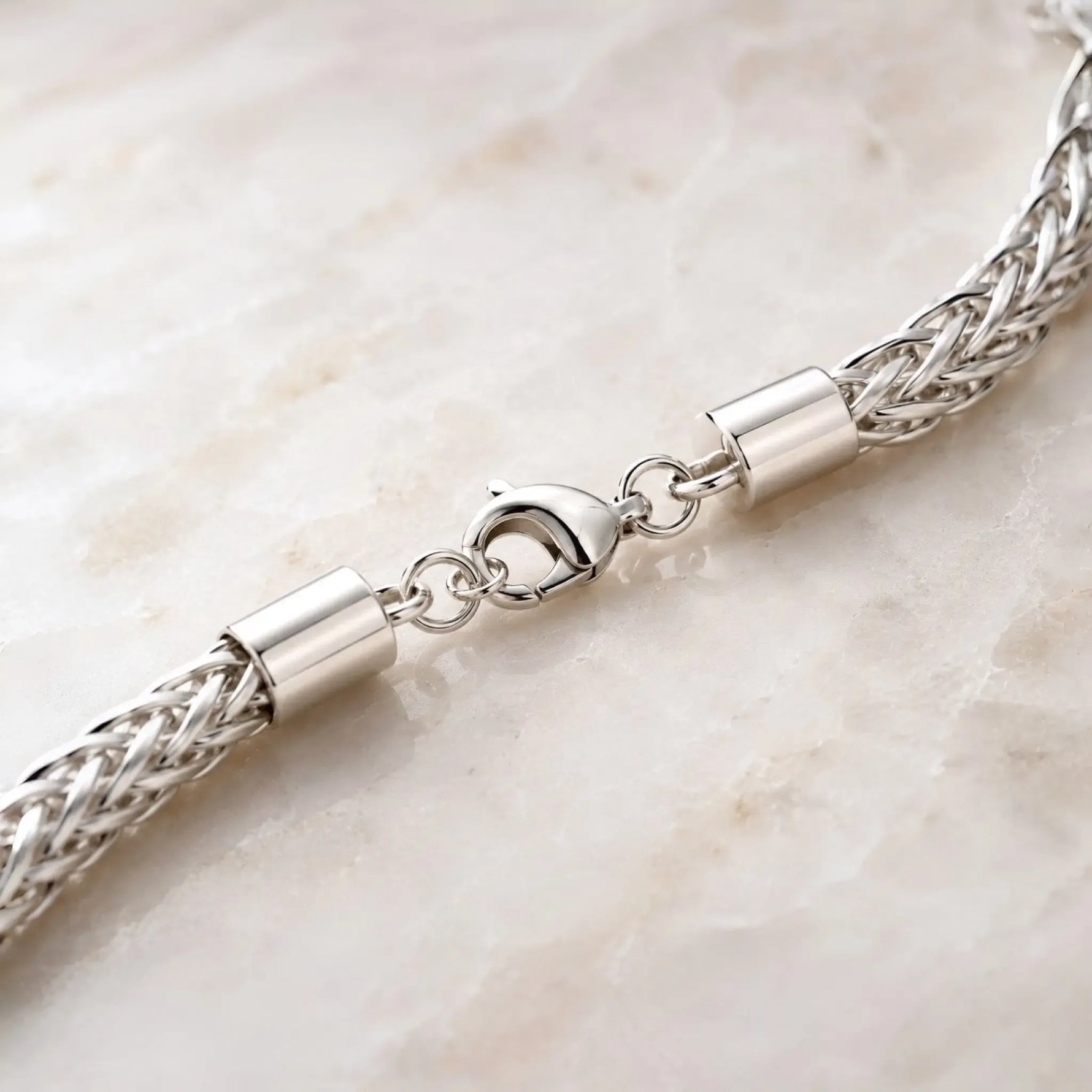 Macro detail of the Evelyn bracelet showing the polished lobster clasp, woven silver termination, end caps and jump rings.