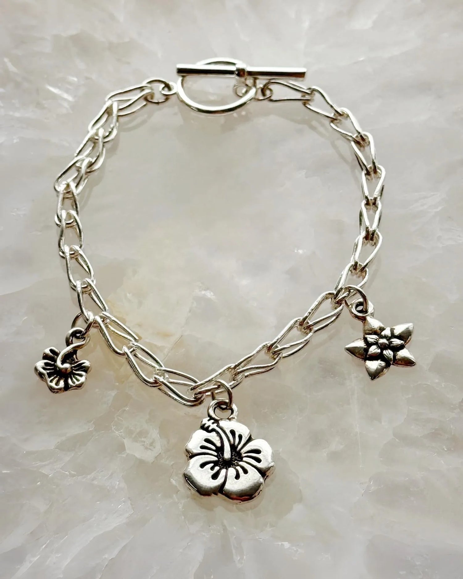 Flora sterling silver charm bracelet with three botanical flower charms on a silver chain, handcrafted by Carabella by Cheryl.