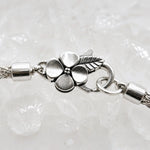Macro detail of the sterling silver apple blossom lobster clasp, woven bracelet termination and jump rings on the Gemma handwoven fine silver bracelet.