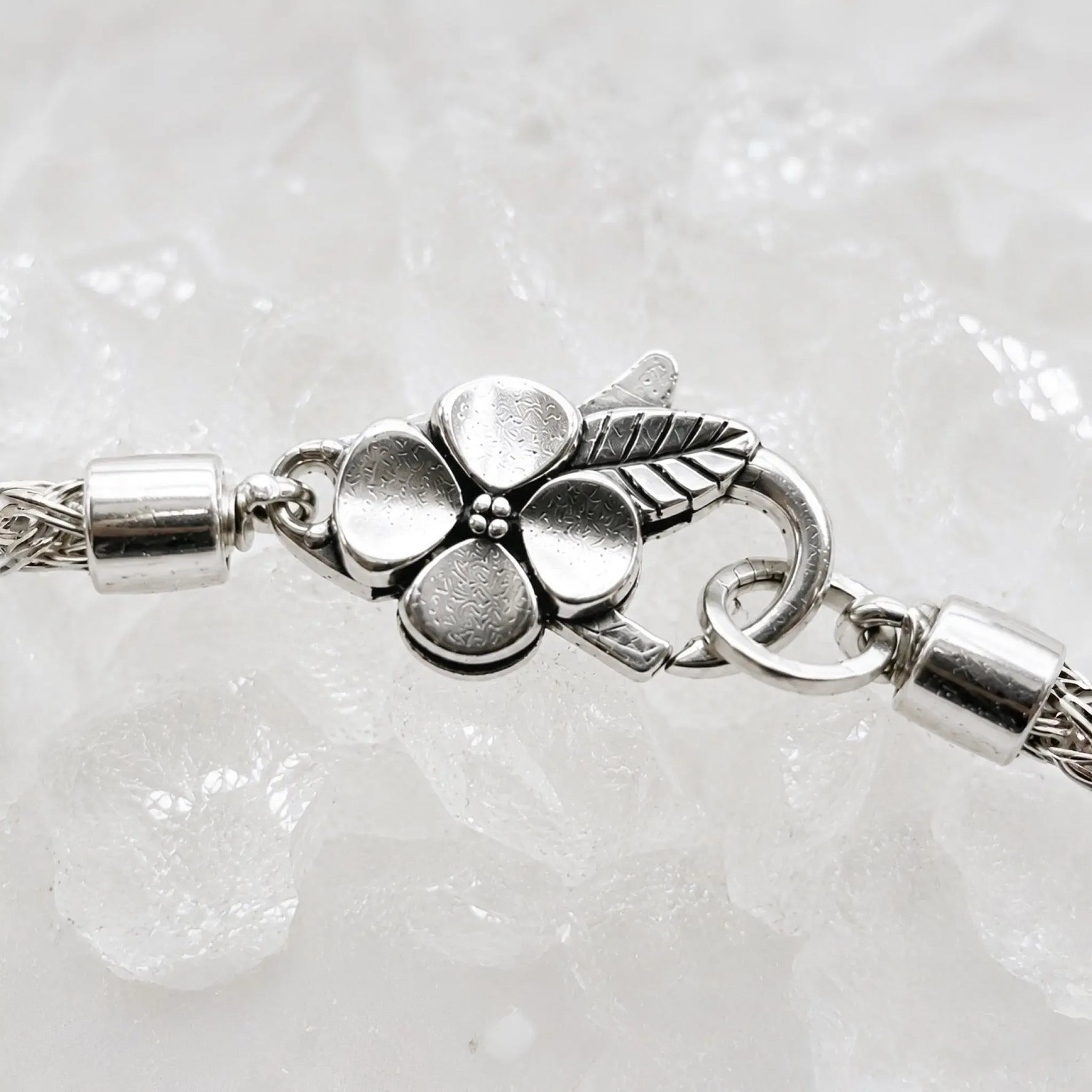 Macro detail of the sterling silver apple blossom lobster clasp, woven bracelet termination and jump rings on the Gemma handwoven fine silver bracelet.