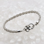 Three-quarter view of the Gemma handwoven .999 fine silver bracelet showcasing the woven silver chain and sterling silver apple blossom clasp on white quartz.