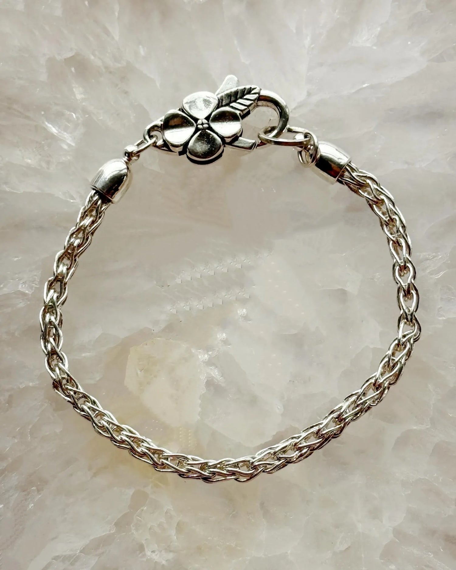 Gemma Fine Silver Bracelet by Carabella by Cheryl showing the handwoven .999 fine silver chain with the signature apple blossom clasp on a crystal background.
