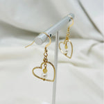 Close-up of Harlow gold earrings featuring luminous pearl and honey opal gemstone