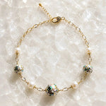 Imperial Blossom Necklace featuring rare Japanese Tensha beads, Swarovski® Crystal Pearls, and gold chain links arranged on a luminous quartz crystal surface in a luxury flat lay photograph.
