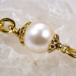 Imperial Blossom Swarovski® Crystal Pearl Necklace detail featuring a luminous pearl, gold-plated bead caps, and gold chain links on a white quartz crystal background.