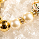 Macro close-up of the Imperial Blossom Bracelet featuring a rare Japanese Tensha bead, Swarovski® Crystal Pearls, crystal rondelle spacers, and gold-plated hematite accents displayed on a luminous quartz crystal background.