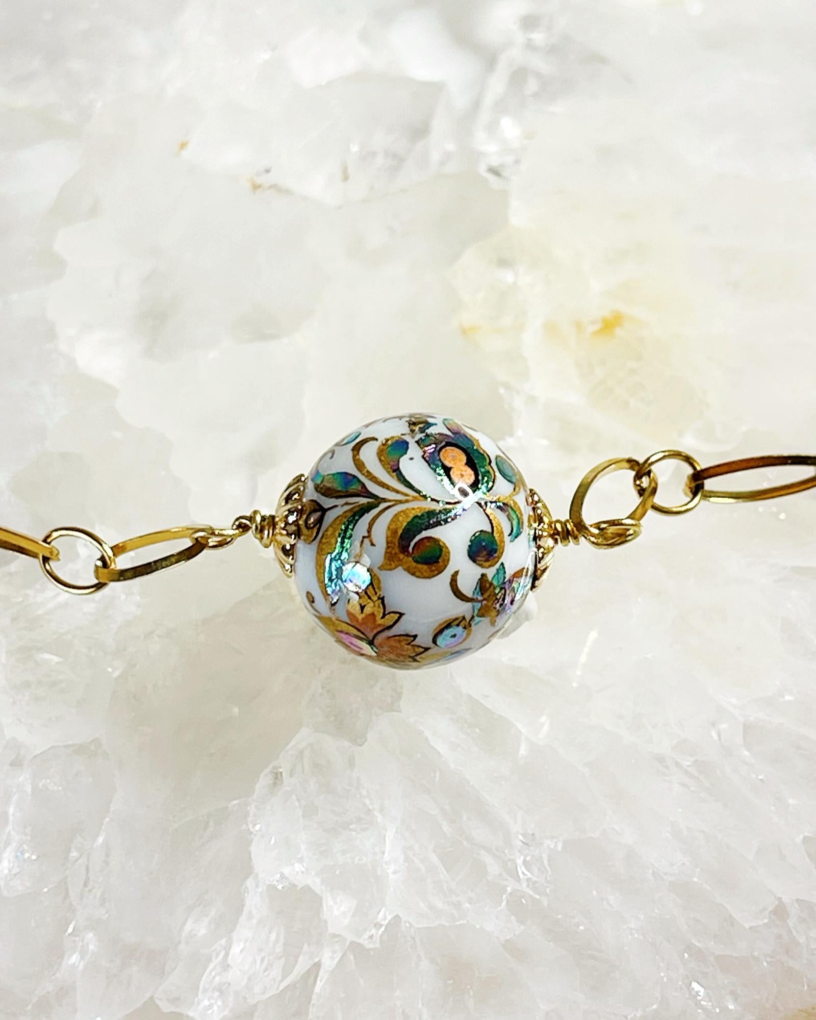 Close-up of the Imperial Blossom Necklace showing the detailed Japanese Tensha bead with floral artwork, framed by gold-plated chain links and Austrian Crystal pearls.