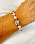 Imperial Blossom Stretch Bracelet worn on wrist, featuring a rare Japanese Tensha bead with floral artwork, Austrian Crystal cream rose pearls, sparkling rondelles, and gold-plated hematite. Handcrafted in Canada by Carabella by Cheryl.