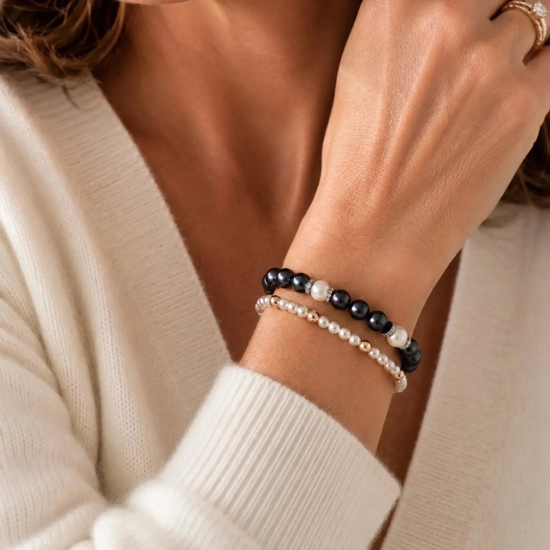 Jan Swarovski® Crystal Pearl Bracelet layered with the Noelani Swarovski® Crystal Pearl Bracelet, combining black and cream Swarovski® Crystal Pearls with delicate cream pearl accents for an elegant stacked bracelet look.