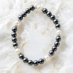 Jan Swarovski® Crystal Pearl Bracelet featuring black and cream Swarovski® Crystal Pearls with crystal rondelles displayed on a luminous white quartz crystal background.