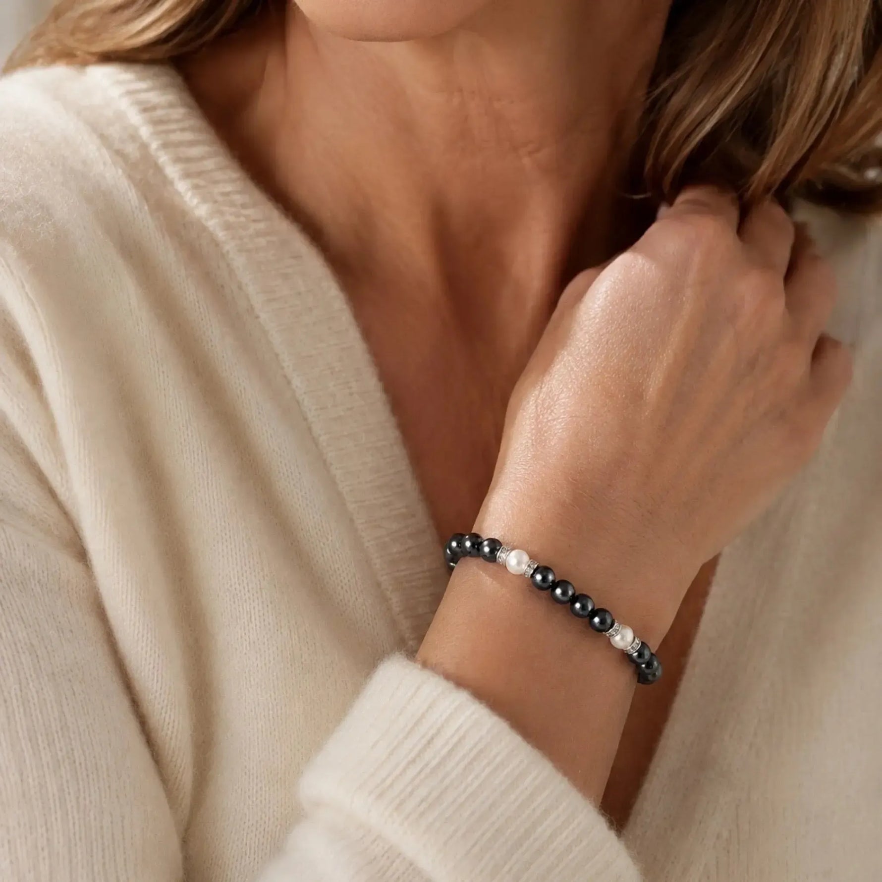 Elegant woman wearing the Jan Swarovski® Crystal Pearl Bracelet with black and cream Swarovski® Crystal Pearls and crystal rondelles, styled with an ivory cashmere sweater.