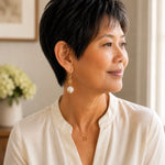 Woman wearing Jewel Cracked Agate Coin Earrings with an ivory blouse in a softly lit luxury interior, showcasing the earrings in an elegant professional lifestyle setting.