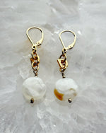 Close-up of Jewel Cracked Agate Earrings showing cracked agate coin beads, gold-plated links, and 14k gold-filled lever-back ear wires displayed on a crystal background.