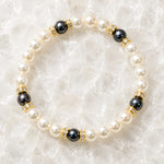 Juanita Swarovski® Crystal Pearl bracelet with cream and dark grey Swarovski® Crystal Pearls, gold crystal rondelles, displayed on luminous white quartz.