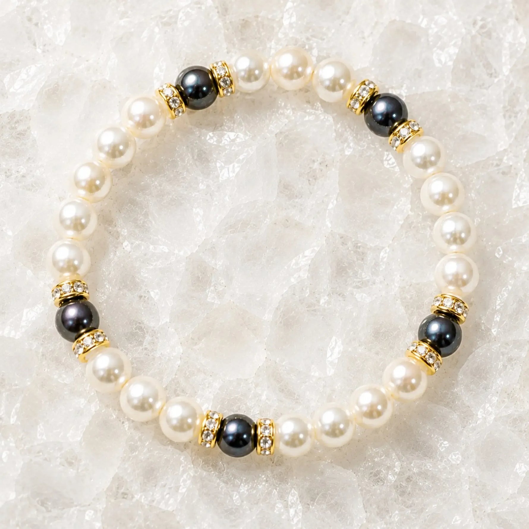 Juanita Swarovski® Crystal Pearl bracelet with cream and dark grey Swarovski® Crystal Pearls, gold crystal rondelles, displayed on luminous white quartz.
